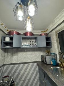 a kitchen with a counter with a sink and lights at Afraah guest house in Yaoundé