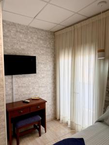 a bedroom with a desk and a television on a wall at Hotel Sancho in Hospitalet de l'Infant +27 photos