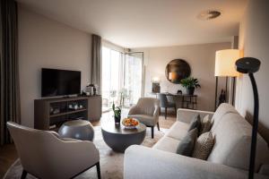 a living room with a couch and chairs and a tv at Hotel Seepark Thun in Thun
