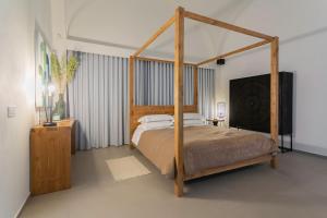 a bedroom with a wooden canopy bed with white pillows at Suite 1926 Luxury Room in Triggiano