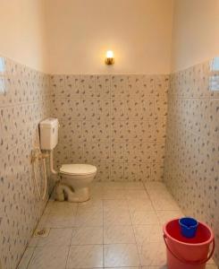 a bathroom with a toilet and a red bucket at Villa 9 degrees north in Sultan Bathery +9 photos