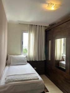 a small bedroom with a bed and a window at Cozy Place Curitiba in Curitiba