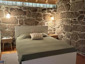 a bedroom with a bed in a stone wall at Serena Nest 01 in Rio Douro