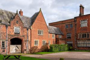 a large red brick building with a large door at West House in High Legh