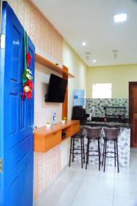 a kitchen with a blue door and a bar with stools at Village vila verde in Itaitu