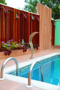 a swimming pool next to a red fence with a pool noodle at Village vila verde in Itaitu