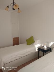 a white bed with a green pillow and a table at A Muradana, Aldán in Pontevedra