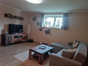 a living room with a couch and a tv and a table at Ferienwohnung Ankerplatz Züssow in Züssow