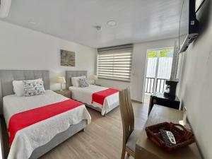 a bedroom with two beds and a chair and a window at Hotel Mar de Corales By CAJASAI in San Andrés