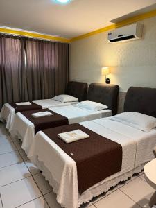 a hotel room with three beds with towels on them at Hotel Estilo in Arapiraca
