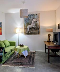 a living room with a green couch and a painting of a horse at Gîte le pré des Colombes in Troche