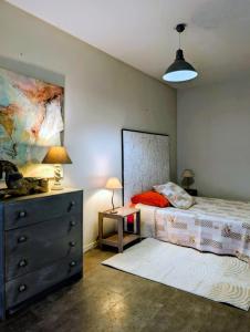 a bedroom with a bed and a dresser with a lamp at Gîte le pré des Colombes in Troche
