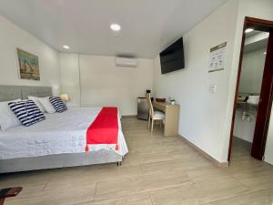 a bedroom with a bed and a desk and a television at Hotel Mar de Corales By CAJASAI in San Andrés