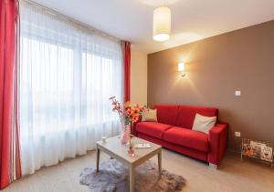 a living room with a red couch and a window at Zenao Appart'hôtels Strasbourg in Strasbourg