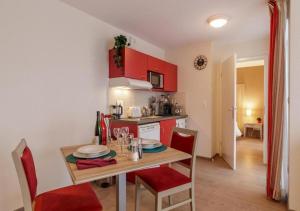 a kitchen with red cabinets and a table with chairs at Zenao Appart'hôtels Strasbourg in Strasbourg