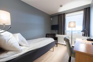 a hotel room with a bed and a desk and a window at Scandic Vadsø in Vadsø +18 photos