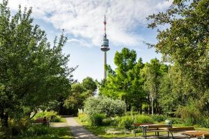 a park with benches and a tv tower in the background at Danube Tower holiday in Vienna