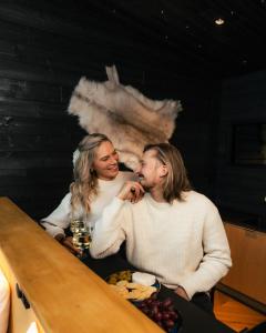 a man and a woman sitting at a table with food at Lapland Glow Chalets in Rovaniemi +25 photos