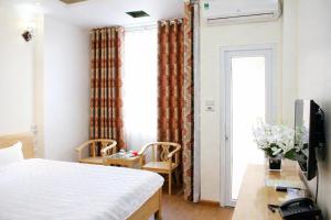 a bedroom with a bed and a desk and a window at Vân Nam Hotel in Cao Bằng