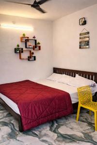 a bedroom with a bed and a yellow chair at Elite Castle Stay in Kottakupam +19 photos