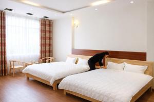 a woman is making two beds in a hotel room at Vân Nam Hotel in Cao Bằng +16 photos