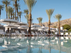a pool with chairs and umbrellas and palm trees at La Quinta Resort & Club in La Quinta