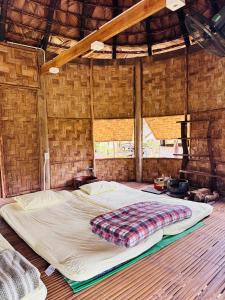 a large bed in a room with a wooden floor at Dhami Farmstay, Đông Giang, Đà Nẵng in Danang