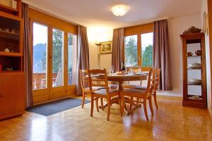 a dining room with a table and chairs and windows at Chalet Miravalle 3 in Wengen