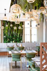 a restaurant with green chairs and tables and chandeliers at Hotel Le Saint Paul in Nice
