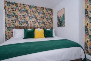 a bedroom with a bed with green and yellow pillows at Stylish Hot Tub House with free parking! in York