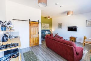 a living room with two red chairs and a kitchen at Modern Barn Conversion in Brackley