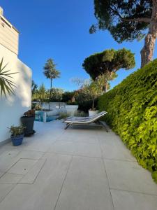 a patio with a bench and some bushes and trees at Villa Portal in La Grande Motte