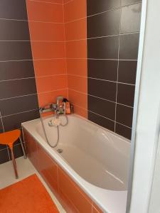 a bath tub in a bathroom with orange and black tiles at Villa Portal in La Grande Motte