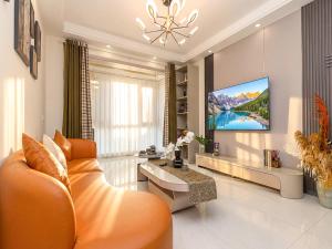 a living room with an orange couch and a tv at Annie Apartment 2105 in Kunming