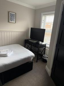 a bedroom with a bed and a desk with a computer at The Wolf Inn in Lowestoft