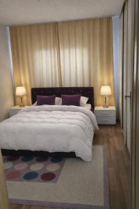 a bedroom with a large white bed with two lamps at Hidden Home in Zenica