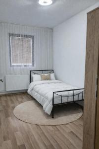 a white bedroom with a large bed with a rug at Hidden Home in Zenica