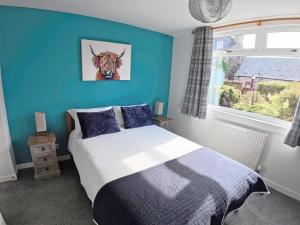a bedroom with a bed with a picture of a cow on the wall at Jessamine Cottage in Blairgowrie