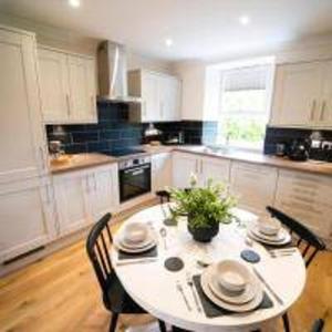 a kitchen with a white table and chairs and a table and chairsktop at Foundry Farm Cottage in Hexham