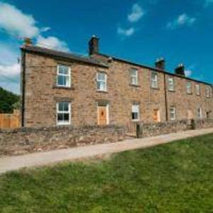 a large brick building sitting on top of a grass field at Foundry Farm Cottage in Hexham