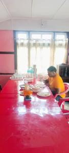 a man sitting at a red table with food on it at SOUPRIYA Impression Homestay in Pedong