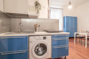 a kitchen with blue cabinets and a washing machine at Long John Apartment in Rome