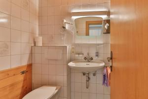a bathroom with a sink and a toilet and a mirror at Bergapartments Wötzinger in Berwang