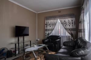 a living room with a leather couch and a tv at Rusty Estate - Self Catering in eMalahleni +79 photos