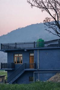 a blue house with a balcony on top of it at Hotel tapobhumi in Barkot