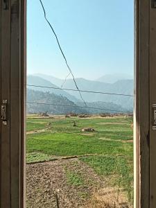 an open window with a view of a field at Hotel tapobhumi in Barkot