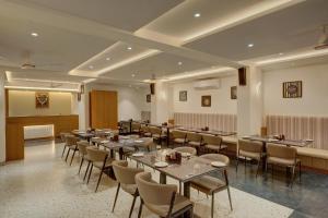 a restaurant with tables and chairs and a podium at Rajpath Beacon Hotel Belagavi in Belgaum