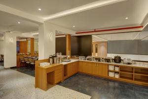 a large kitchen with wooden cabinets and a table at Rajpath Beacon Hotel Belagavi in Belgaum