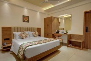 a bedroom with a large bed and a desk at Rajpath Beacon Hotel Belagavi in Belgaum