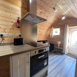a kitchen with a stove and a counter top at Foundry Farm Arch- pod inspired home in Hexham +12 photos